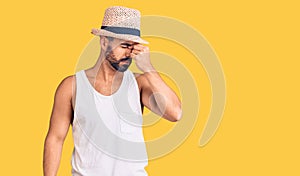 Young hispanic man wearing casual summer hat tired rubbing nose and eyes feeling fatigue and headache