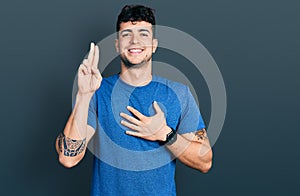 Young hispanic man wearing casual t shirt smiling swearing with hand on chest and fingers up, making a loyalty promise oath
