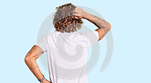 Young hispanic man wearing casual white tshirt backwards thinking about doubt with hand on head