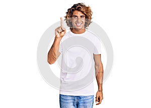 Young hispanic man wearing casual white tshirt pointing finger up with successful idea