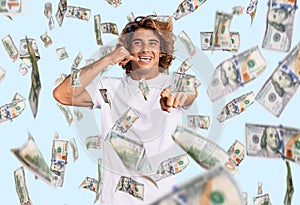 Young hispanic man wearing casual white tshirt smiling doing talking on the telephone gesture and pointing to you