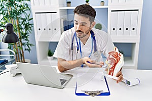 Young hispanic man wearing doctor uniform having teleconsultation at clinic