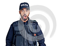 Young hispanic man wearing police uniform afraid and shocked with surprise and amazed expression, fear and excited face