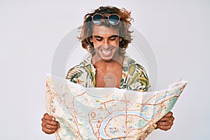 Young hispanic man wearing summer style holding map smiling and laughing hard out loud because funny crazy joke