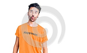 Young hispanic man wearing t shirt with happiness word message making fish face with lips, crazy and comical gesture