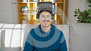Young hispanic man wearing virtual reality glasses smiling at home