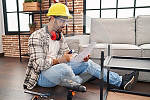 Young hispanic man worker reading instructions holding screwdriver at home