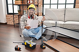 Young hispanic man worker reading instructions holding wrench at home
