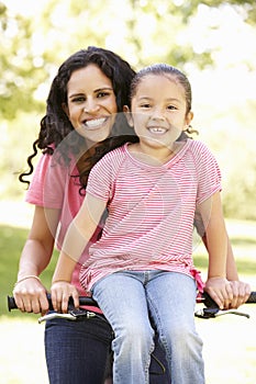 Young Hispanic Mother And Daughter Cycling In Park