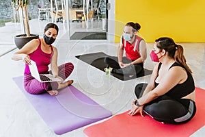 Young hispanic people with protective masks taking yoga class using the computer in Latin America