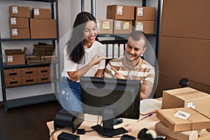 Young hispanic people working at small business ecommerce smiling happy pointing with hand and finger