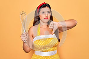 Young hispanic pin up woman wearing fashion sexy 50s style holding cooking whisk blender with angry face, negative sign showing