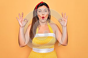 Young hispanic pin up woman wearing fashion sexy 50s style over yellow background looking surprised and shocked doing ok approval