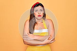 Young hispanic pin up woman wearing fashion sexy 50s style over yellow background shaking and freezing for winter cold with sad