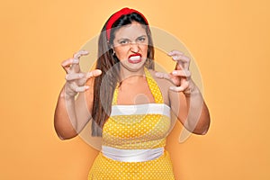 Young hispanic pin up woman wearing fashion sexy 50s style over yellow background Shouting frustrated with rage, hands trying to