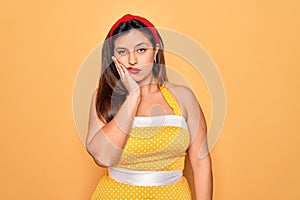 Young hispanic pin up woman wearing fashion sexy 50s style over yellow background thinking looking tired and bored with depression