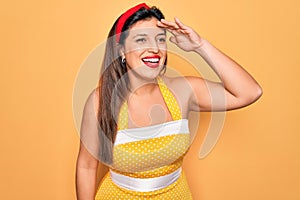 Young hispanic pin up woman wearing fashion sexy 50s style over yellow background very happy and smiling looking far away with