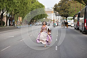 Young, Hispanic, pretty, brunette woman, wearing an elegant vintage violet dress, running funny on the road in the middle of