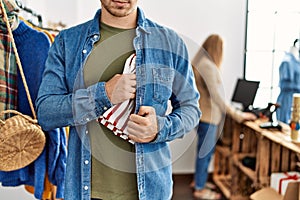 Young hispanic robber man stealing shirt at clothes store