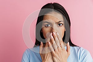 Young hispanic shocked woman covering her mouth and looking at camera