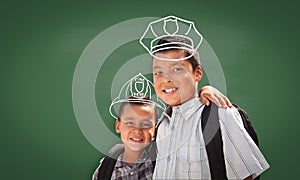 Young Hispanic Student Boy Wearing Backpack Front Of Blackboard with Fireman Helmet And Policeman Hat Drawn In Chalk Over Heads