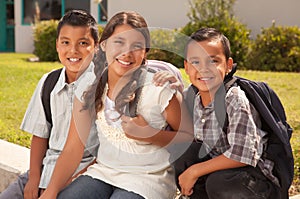 Young Hispanic Student Children Wearing Backpacks On School Campus