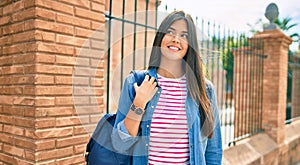 Young hispanic student girl smiling happy walking at the city