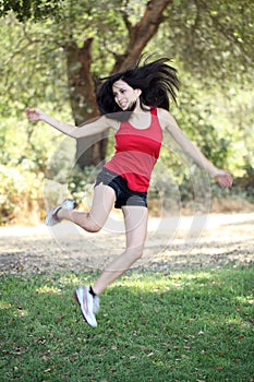 Young hispanic teen woman jumping outdoors