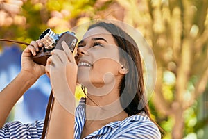 Young hispanic tourist girl smiling happy using camera at the park