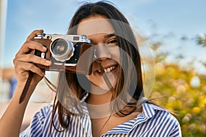 Young hispanic tourist girl smiling happy using camera at the park