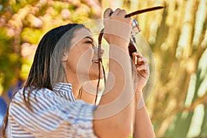 Young hispanic tourist girl smiling happy using camera at the park