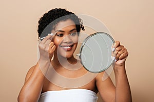 Young Hispanic Woman Applying Makeup in Front of Mirror