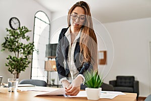 Young hispanic woman business worker reading paperwork working at office