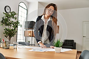 Young hispanic woman business worker reading paperwork working at office