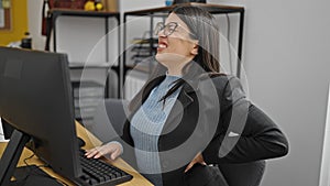 Young hispanic woman business worker suffering for back ache at office