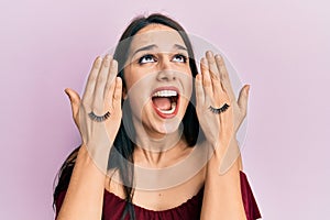 Young hispanic woman covering eyes with hands and fake lashes angry and mad screaming frustrated and furious, shouting with anger