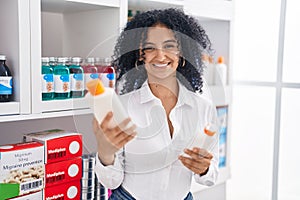 Young hispanic woman customer smiling confident choosing sunscreen lotion at pharmacy