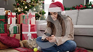 Young hispanic woman with dog shopping with smartphone and credit card celebrating christmas at home