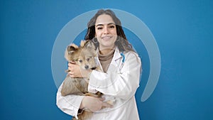 Young hispanic woman with dog veterinarian smiling confident hugging over isolated blue background