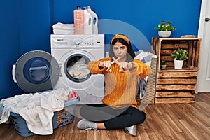 Young hispanic woman doing laundry rejection expression crossing fingers doing negative sign
