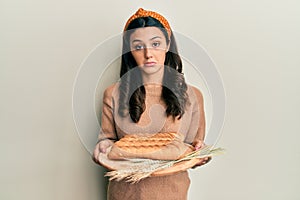Young hispanic woman holding bread depressed and worry for distress, crying angry and afraid
