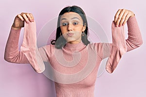 Young hispanic woman holding socks puffing cheeks with funny face