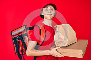 Young hispanic woman holding take away paper bag puffing cheeks with funny face