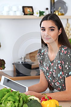 Young hispanic woman is making online shopping by tablet computer and credit card. Housewife found new recipe for