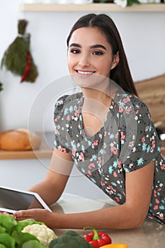 Young hispanic woman is making online shopping by tablet computer and credit card. Housewife found new recipe for