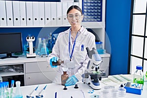 Young hispanic woman scientist measuring liquid at laboratory