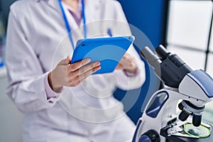 Young hispanic woman scientist using touchpad working at laboratory