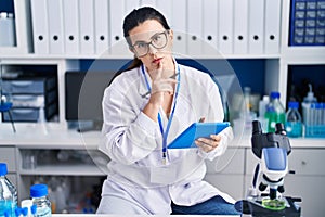 Young hispanic woman scientist using touchpad working at laboratory