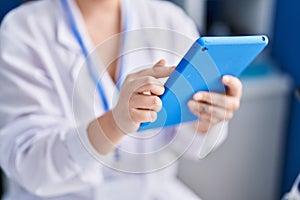 Young hispanic woman scientist using touchpad working at laboratory