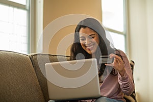 Young Hispanic woman shopping online at home.